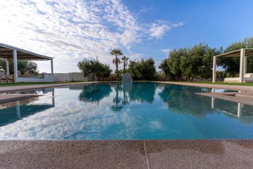 a swimming pool in a villa with blue sky and trees at Villa Daïs - Marrakech in Marrakech