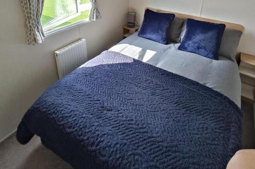 a bed with a blue comforter in a bedroom at Golden Sands 3-Bed Caravan Parking & Pet Friendly in Rhyl