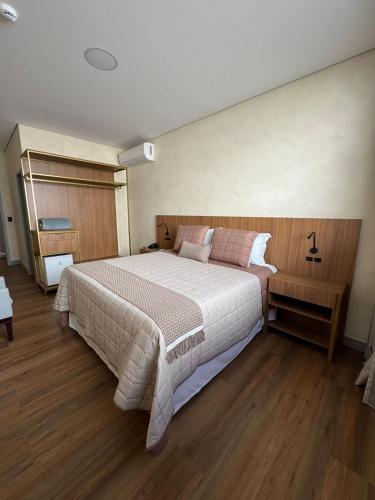 a bedroom with a large bed and wooden floors at Pousada Big Bear II in Campos do Jordão