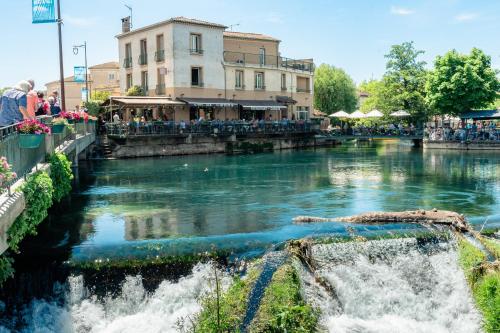 un fiume con una cascata in una città di Le Bassin Hôtel Restaurant a LʼIsle-sur-la-Sorgue