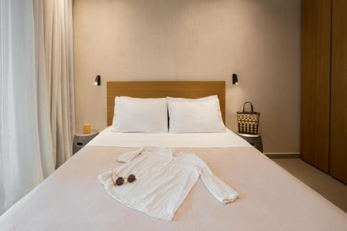 a white bed with a robe and sunglasses on it at Pnoes Luxury Suites in Paliouri