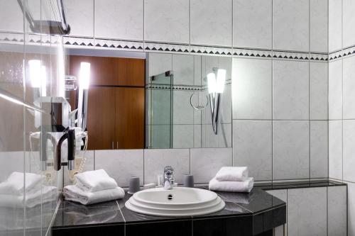 a bathroom with a sink and a mirror at Sport- und Tagungshotel De Poort in Goch