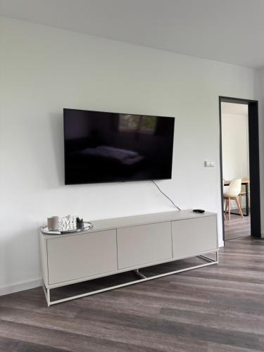 a white living room with a large tv on a wall at Remark Studios - Moderne Apartments Misburg in Hannover