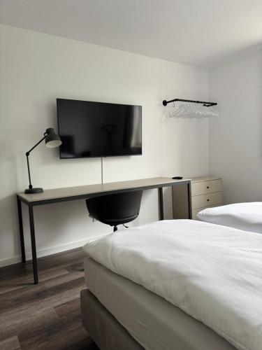 a bedroom with a desk with a television on a wall at Remark Studios - Moderne Apartments Misburg in Hannover
