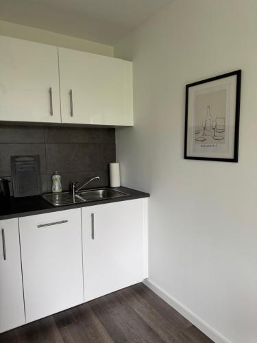 a kitchen with white cabinets and a sink at Remark Studios - Moderne Apartments Misburg in Hannover