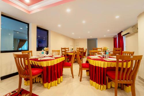 ein Restaurant mit Tischen und Stühlen sowie roten und gelben Tischdecken in der Unterkunft Treebo Classic Highway Side in Thiruvananthapuram