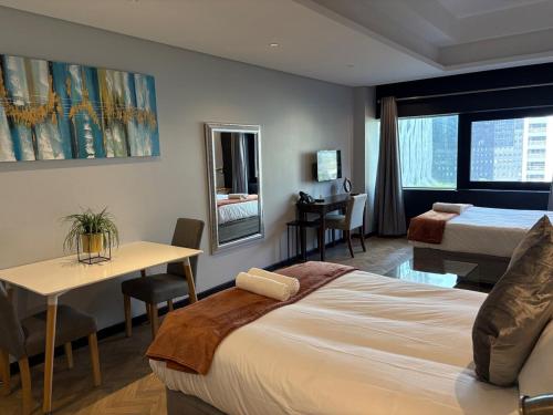 a hotel room with a bed and a table and a desk at Executive Hotel Apartment at Oynx in Cape Town