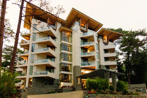 a large white building with balconies and trees at Grand Sierra Pines Baguio in Baguio