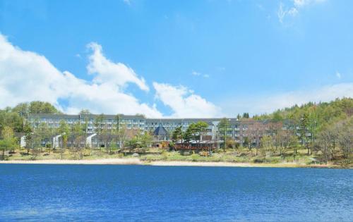 a large building on the shore of a body of water at Izumigo AMBIENT Tateshina Hotel in Tateshina