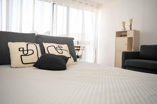 un lit avec des oreillers noirs et blancs et une chaise dans l'établissement Studio Saint Cyprien plage, à Saint Cyprien Plage