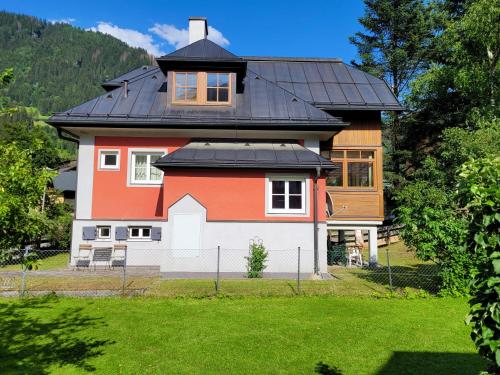 a large house with a black roof at Villa Schnuck - das rote Ferienhaus in Bad Gastein