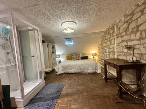 a bedroom with a bed and a stone wall at Petite Maison avec jardin privée in Savigny-en-véron