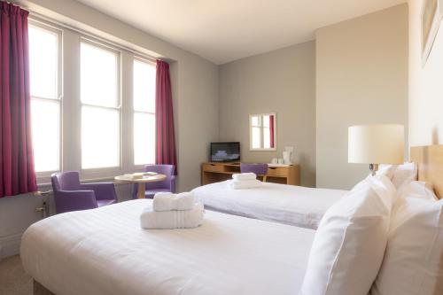 a hotel room with two beds and purple chairs at The Marine Hotel in Llandudno