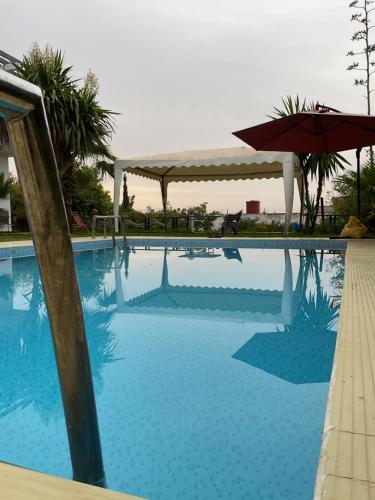 a large swimming pool with an umbrella next to it at Belle maison de campagne in Kenitra