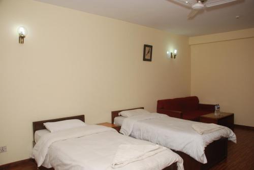 a room with two beds and a red chair at Kathmandu Madhuban Guest House in Kathmandu