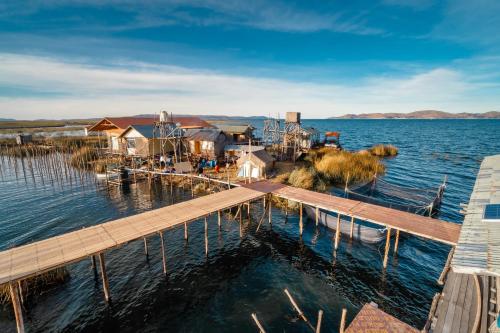 a dock on a body of water with houses at Uros Titicaca Lodge in Puno