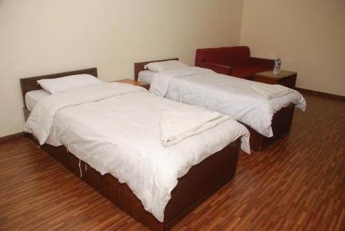 two beds in a room with a red chair at Kathmandu Madhuban Guest House in Kathmandu