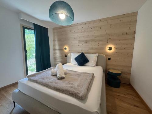 una camera da letto con un grande letto bianco e una parete in legno di Kayla du Mont-Blanc - Espace bien etre - Piscine a Les Houches