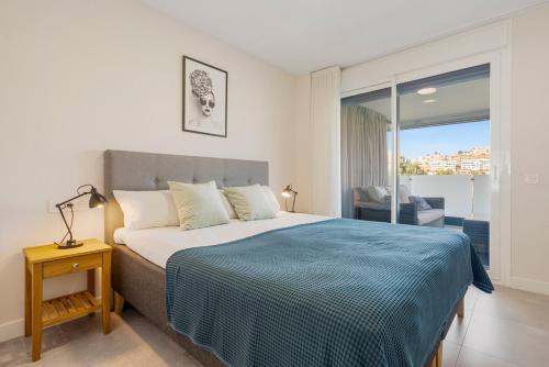a bedroom with a bed with a blue blanket at Luxury 3 BR Apartment with Terrace, pool & gym in Mijas Costa