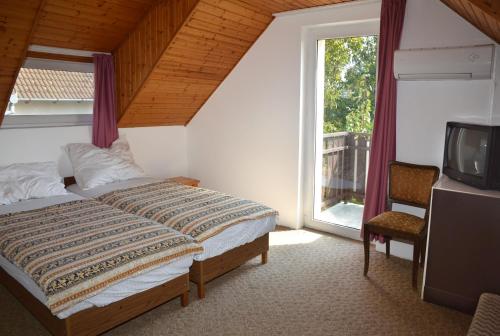 a bedroom with a bed and a tv and a window at Haus Pelso in Gyenesdiás