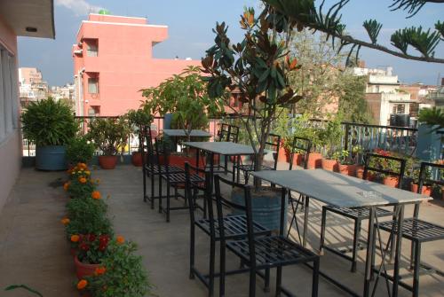 uma fila de mesas e cadeiras numa varanda com plantas em Kathmandu Madhuban Guest House em Catmandu