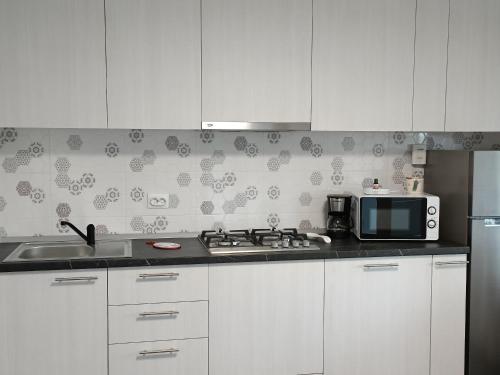 a kitchen with white cabinets and a microwave and a sink at Colț de lavandă in Braşov