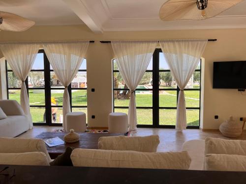 a living room with white furniture and large windows at Villa Daïs - Marrakech in Marrakech