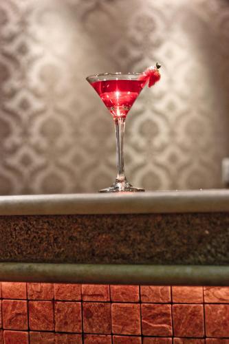 a red drink in a martini glass sitting on a counter at Hotel Meridional in Fortaleza