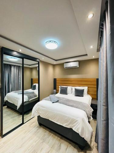 a bedroom with two beds and a mirror at Que Self Catering Apartments in Gaborone