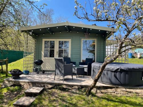 a green shed with a table and chairs on a patio at Lodge with HotTub-Garden-PetsOK-Bbq-MountainViews in Brecon