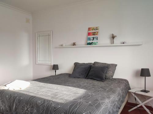 a bedroom with a bed with a gray comforter at Luar dos Magos in Salvaterra de Magos
