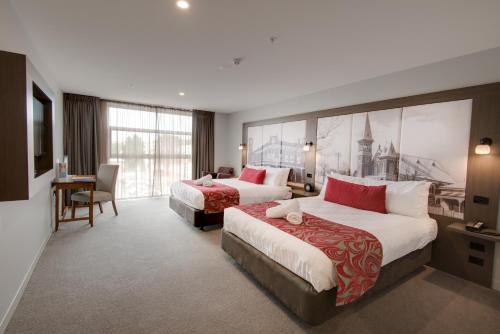 a hotel room with two beds and a desk at Mercure Warragul in Warragul