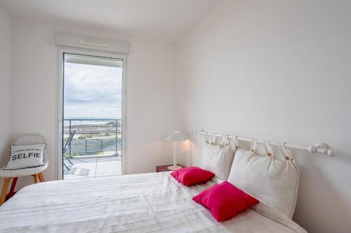 a white bedroom with a large bed with pink pillows at Les voiles du large in Les Sables-dʼOlonne
