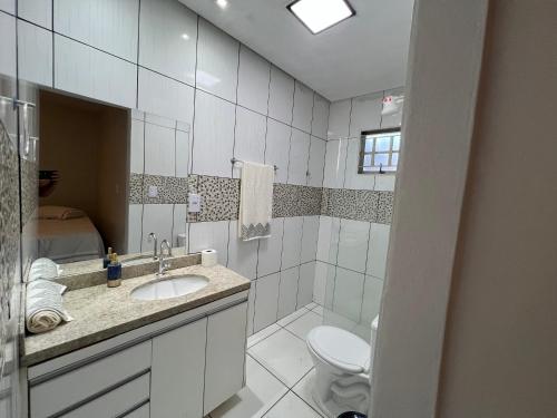 a white bathroom with a sink and a toilet at Casa para eventos e acomodações in Goiânia
