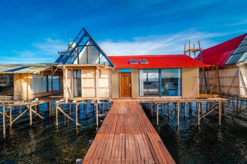 a house on the water next to a dock at Uros Titicaca Lodge in Puno