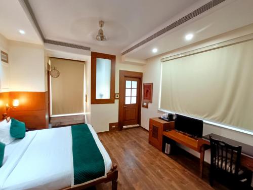 a bedroom with a bed and a desk with a television at Hotel Sun Grand in Agra