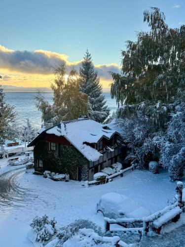 a house covered in snow next to the water at Pailahue Cabañas Lodge in San Carlos de Bariloche