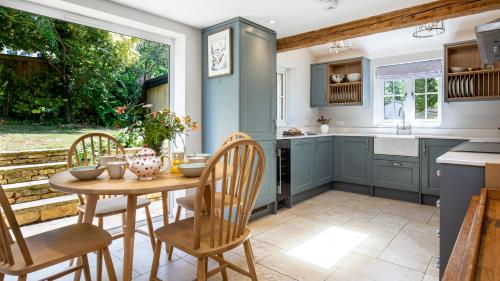 Una cocina con una mesa y sillas en una cocina. en Inglenook Cottage, en Charlbury