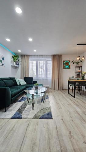 a living room with a green couch and a glass table at METIS Apartment in Martin