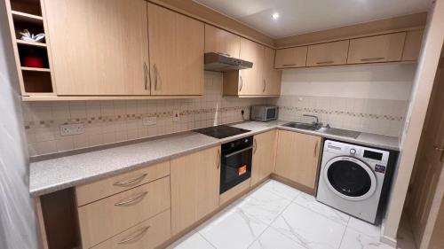 a kitchen with wooden cabinets and a washer and dryer at comfy residence in Moffat
