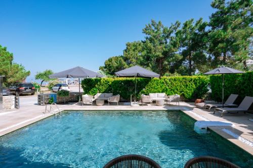 a swimming pool with chairs and umbrellas at Sentimento Sea Breeze in Skala Prinou