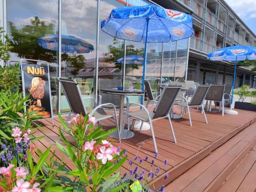 a group of chairs and tables with umbrellas on a deck at Orange Wings Wiener Neustadt in Wiener Neustadt