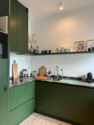 a kitchen with green cabinets and a sink at DUNE, Maison Littoral by BLOSS stylish apartment with garden and terrace in De Haan