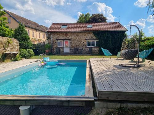 une piscine avec une terrasse en bois et une maison dans l'établissement Jolie maison de centre-ville: Le Tournesac, à Héricourt