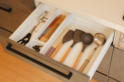 a drawer filled with utensils in a cabinet at 野波一棟貸古民家 