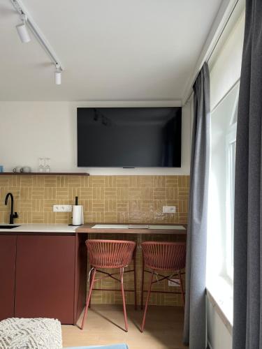 a kitchen with two chairs and a tv on the wall at Business Accommodation 'Eclectic Living' Nomad in Geel