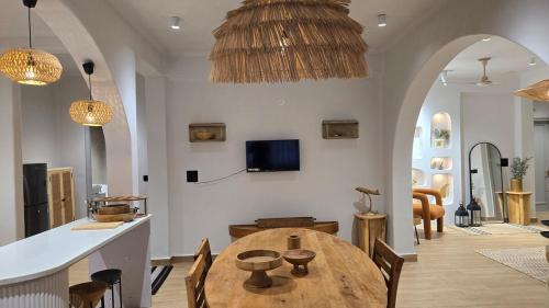 a living room with a wooden table and a kitchen at Ganga Aahana Retreat - Luxury Home Vibe & Ganga View in Rishīkesh