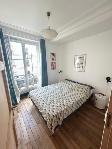 une chambre avec un lit et une grande fenêtre dans l'établissement Bel appartement quartier de la Roquette by Weekome, à Paris