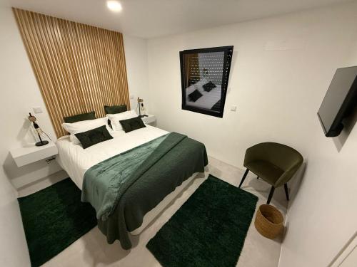 ein Schlafzimmer mit einem Bett und einem Stuhl und einem Fernseher in der Unterkunft Casa do Lago das Freiras in Ribeira Grande