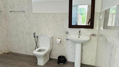 a bathroom with a toilet and a sink at Kujaku in Arugam Bay